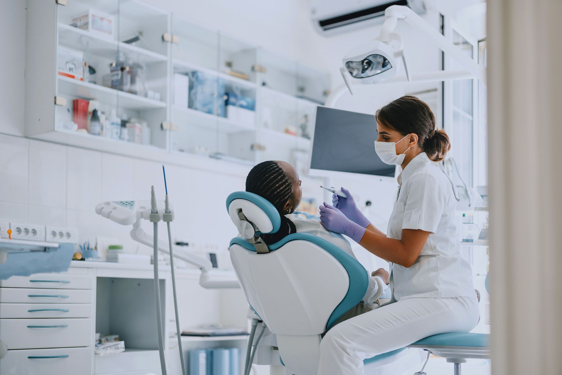 Dentist in mask and gloves administering injection to patient in dental chair. Clinic setting.