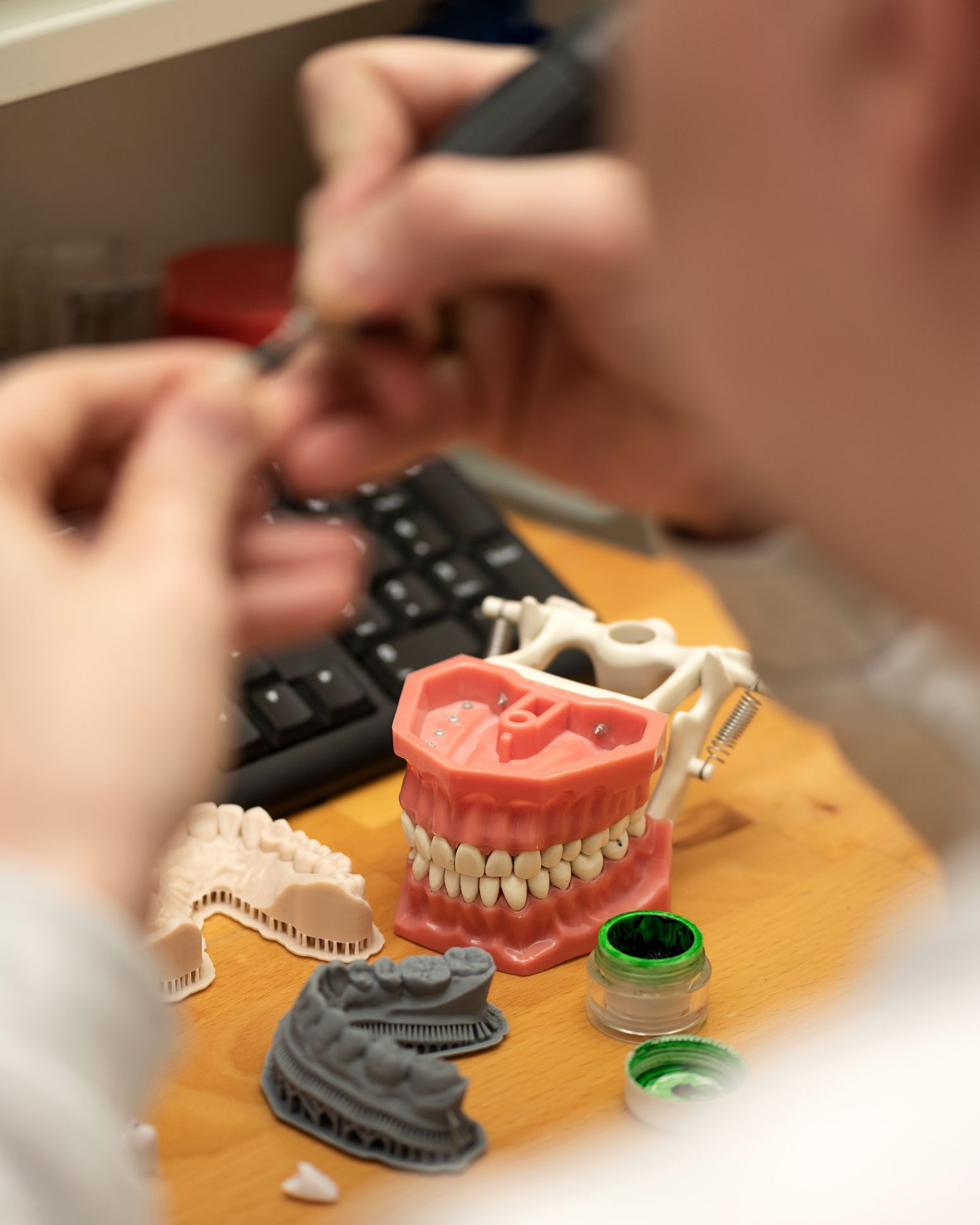 Dentist matching tooth shade to a model using a color guide in a dental lab setting.
