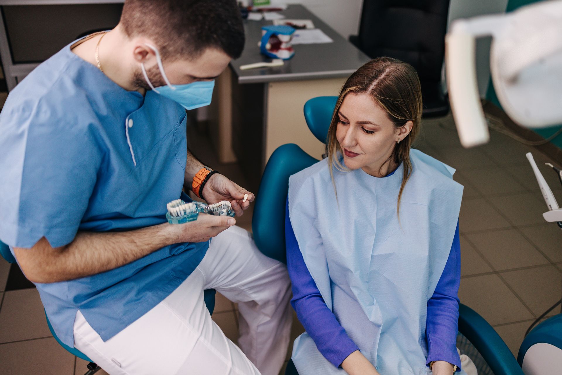 Dentist showing patient a dental model in an office.