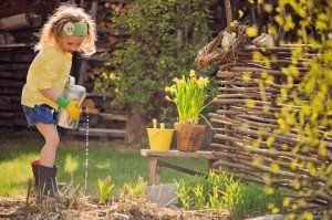 cute child girl playing little gardener and watering flowers in