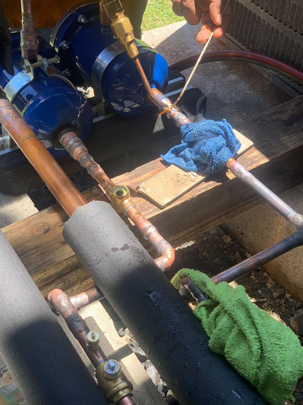 Una persona está soldando tubos de cobre en un piso de madera.