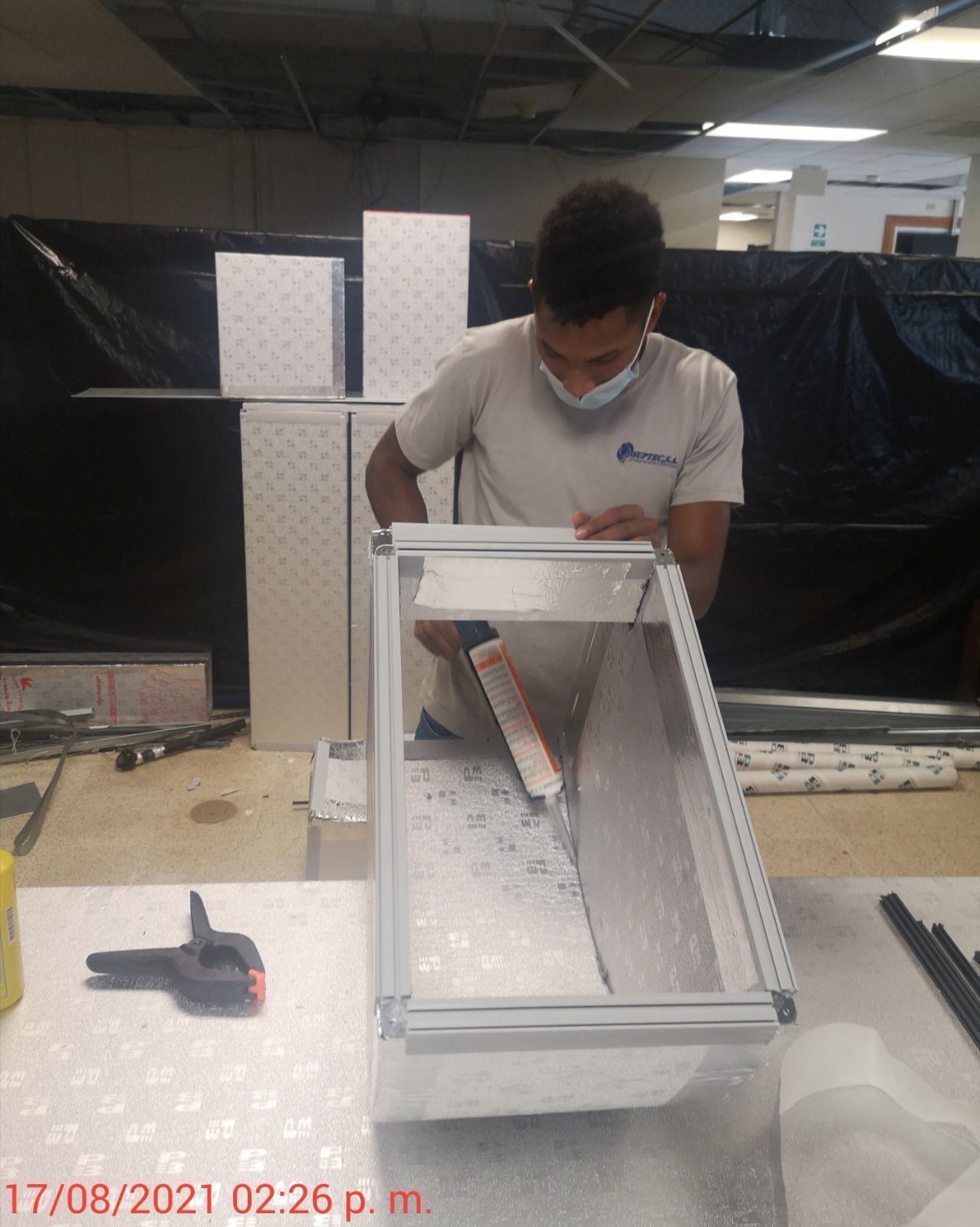 Un hombre que lleva una máscara está trabajando en una pieza de metal.