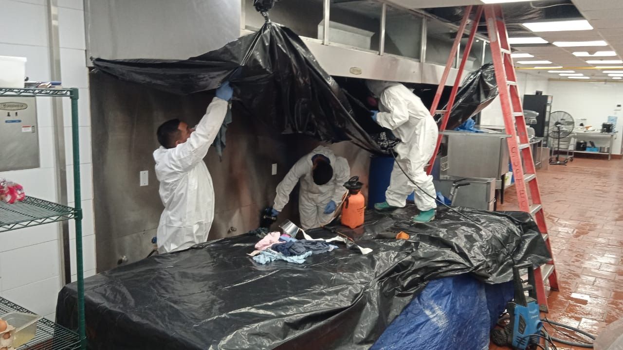 Un grupo de personas con trajes de protección están trabajando en una cocina.