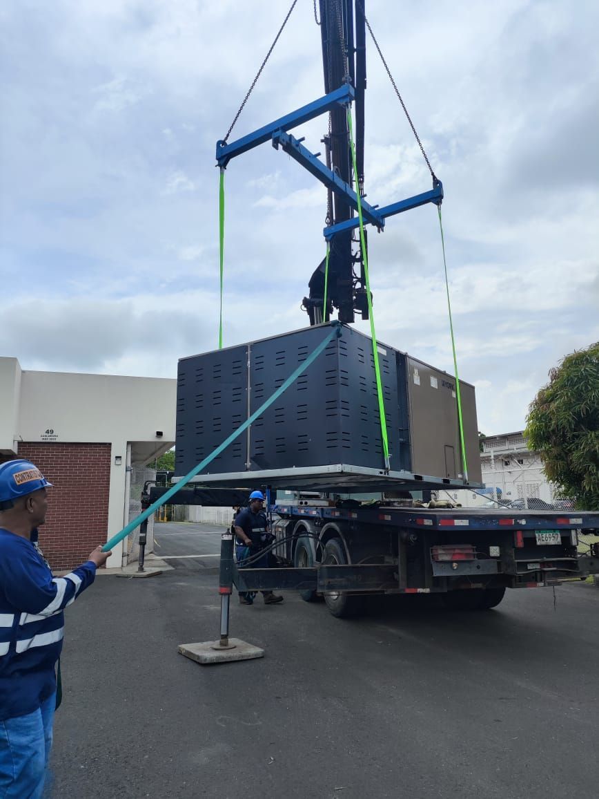 Un hombre está de pie junto a un camión que está siendo levantado por una grúa.