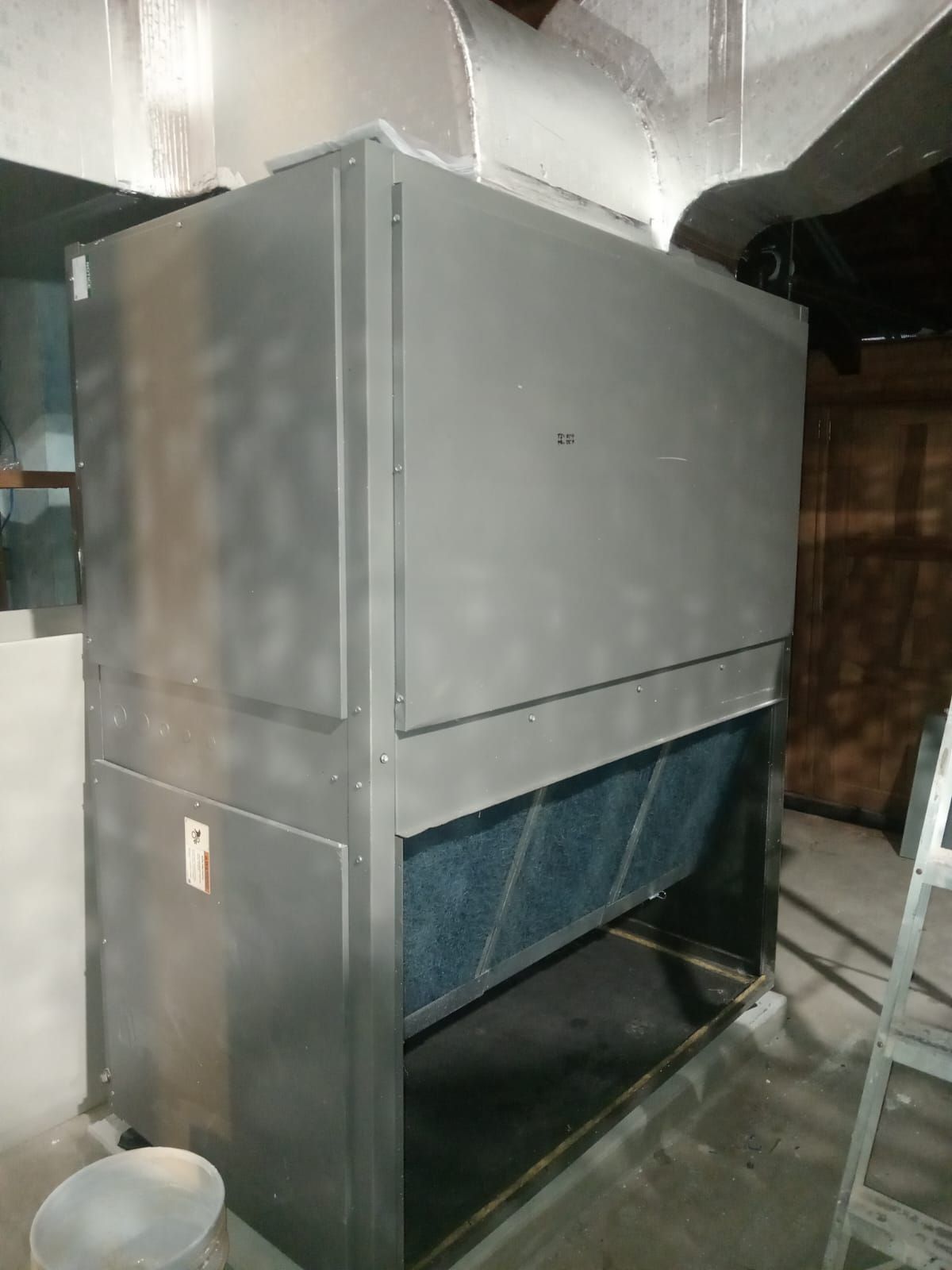 Una gran máquina de acero inoxidable se encuentra en una habitación al lado de una escalera.