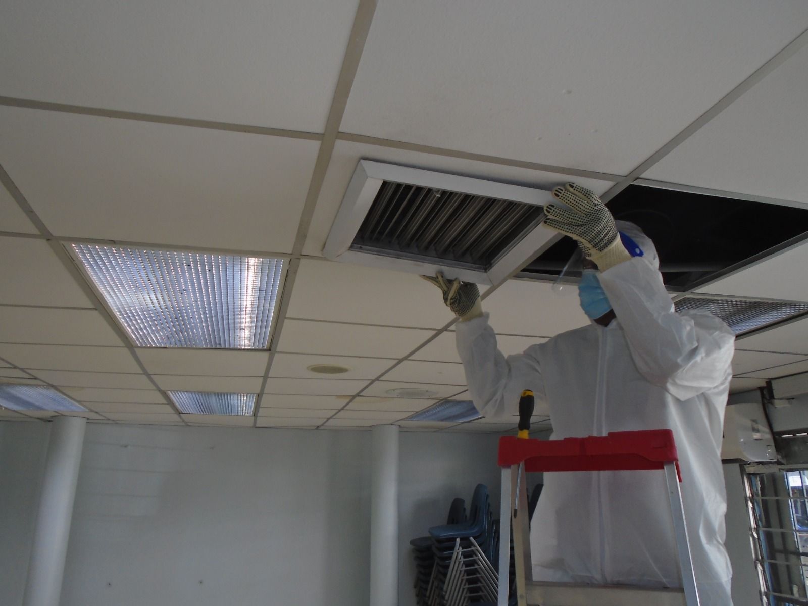 Un hombre con un traje de protección está trabajando en un respiradero del techo.