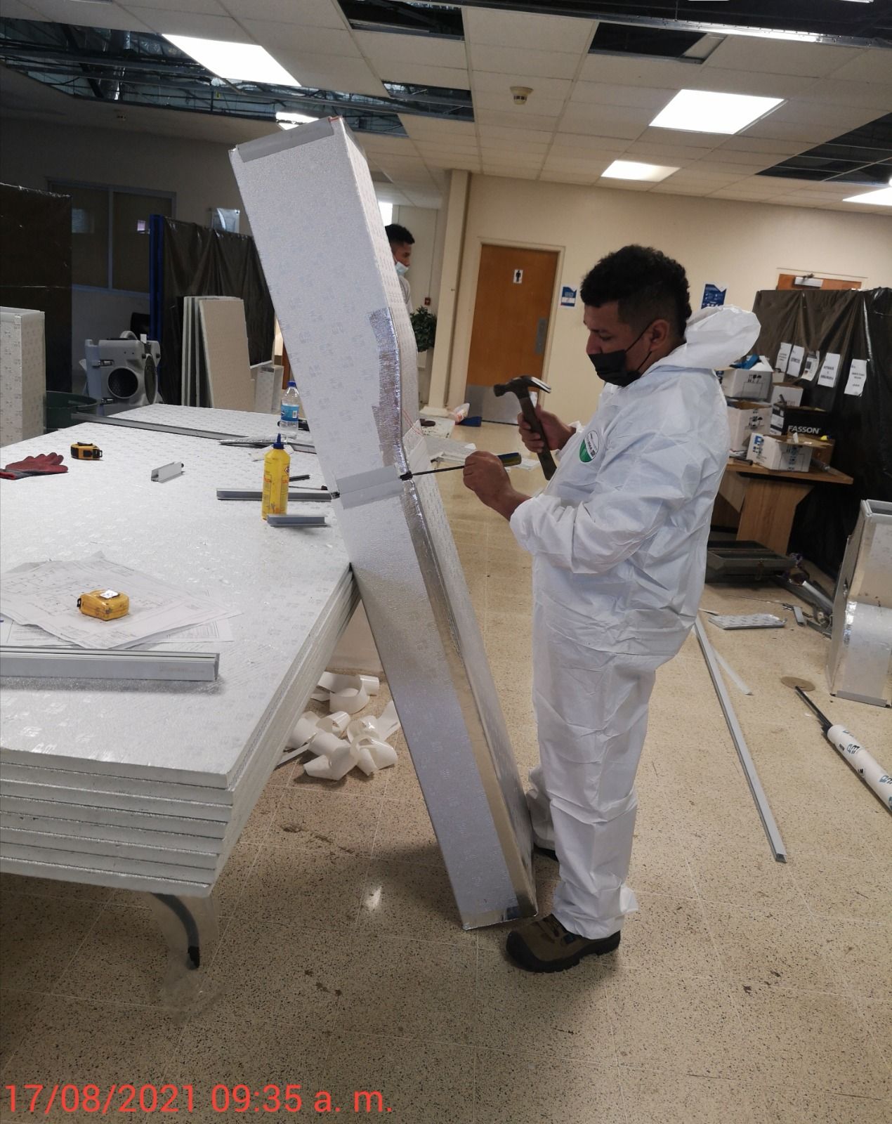 Un hombre con un traje blanco sostiene un martillo en una habitación.