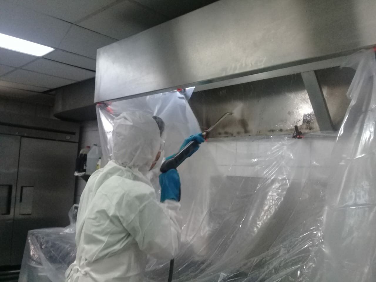 Una persona está limpiando una campana de acero inoxidable con una bolsa de plástico.