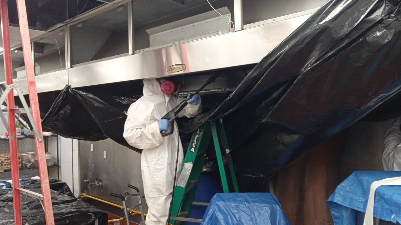Un hombre con un traje de protección está de pie en una escalera en una cocina.