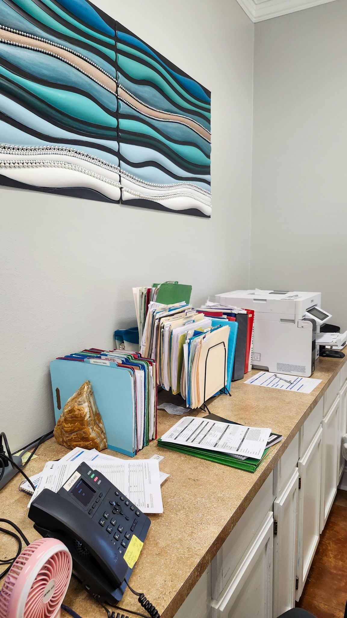 There is a painting on the wall above the desk.