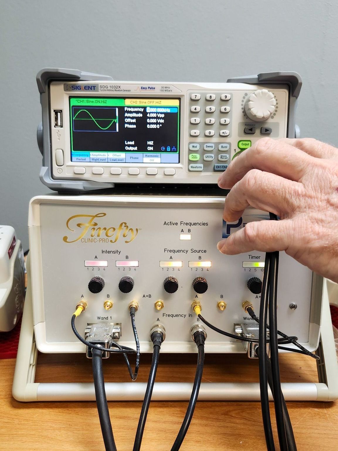 A person is using a digital oscilloscope on a wooden table.