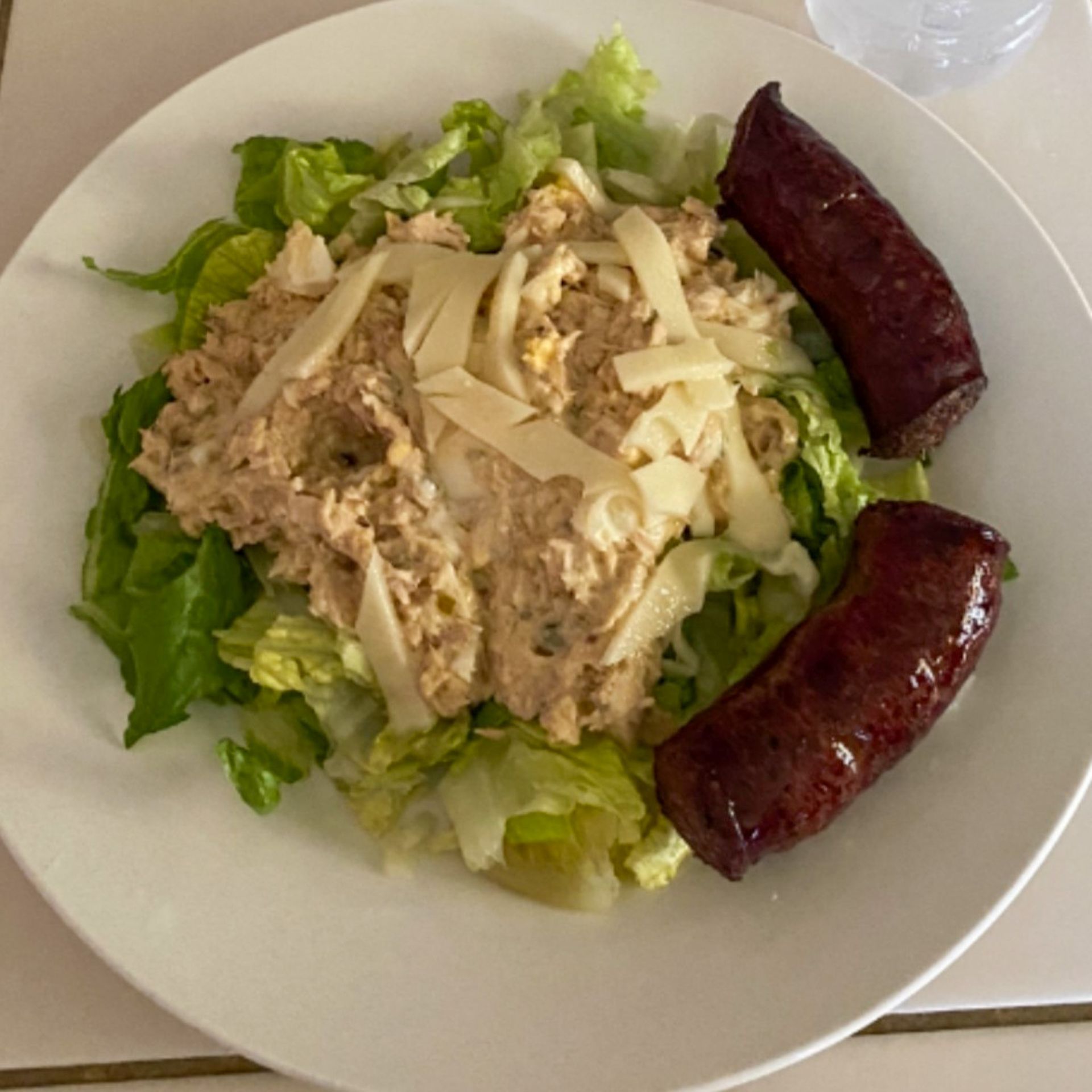 A white plate topped with a salad and two sausages