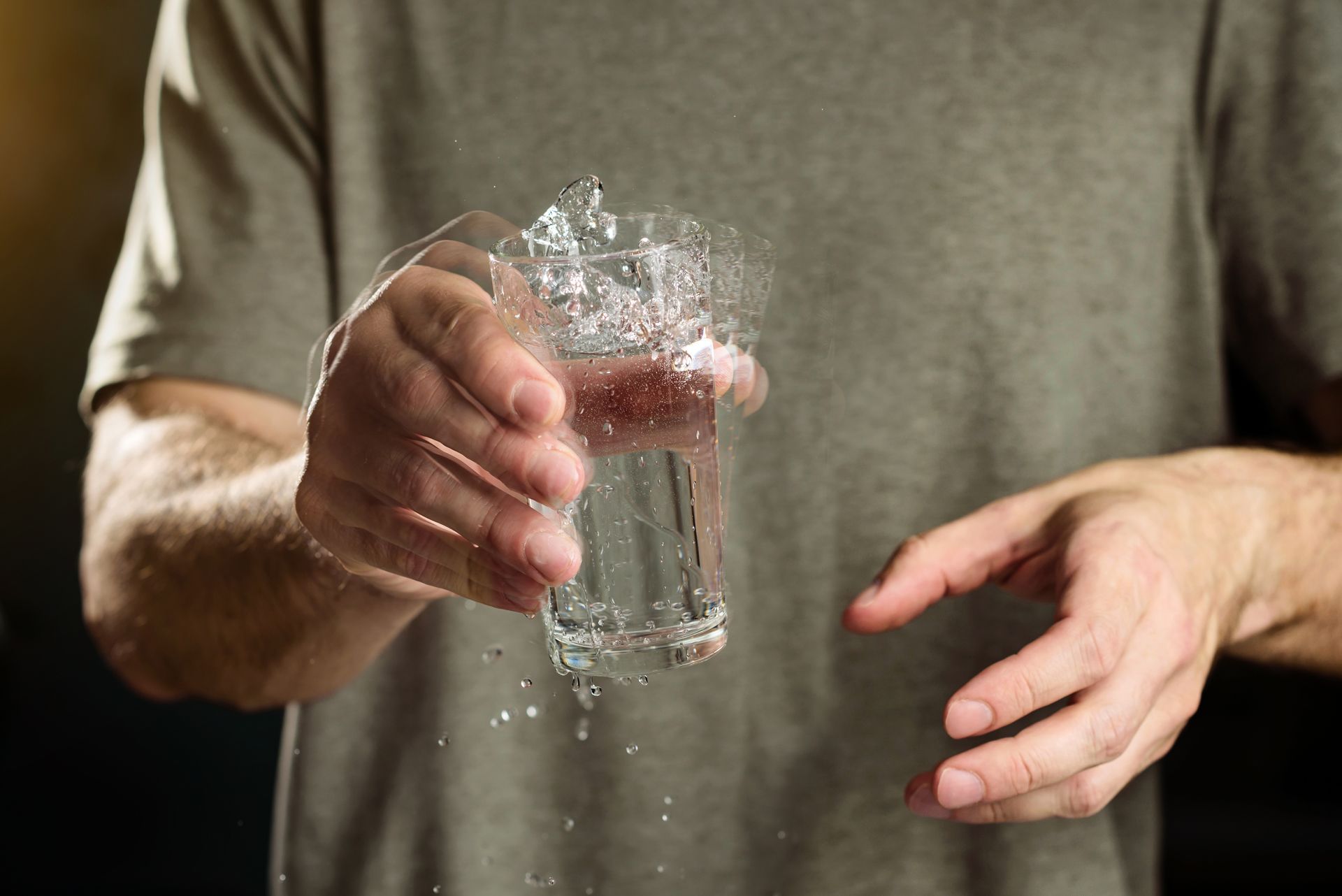 A man is holding a glass of water in his shaky hands