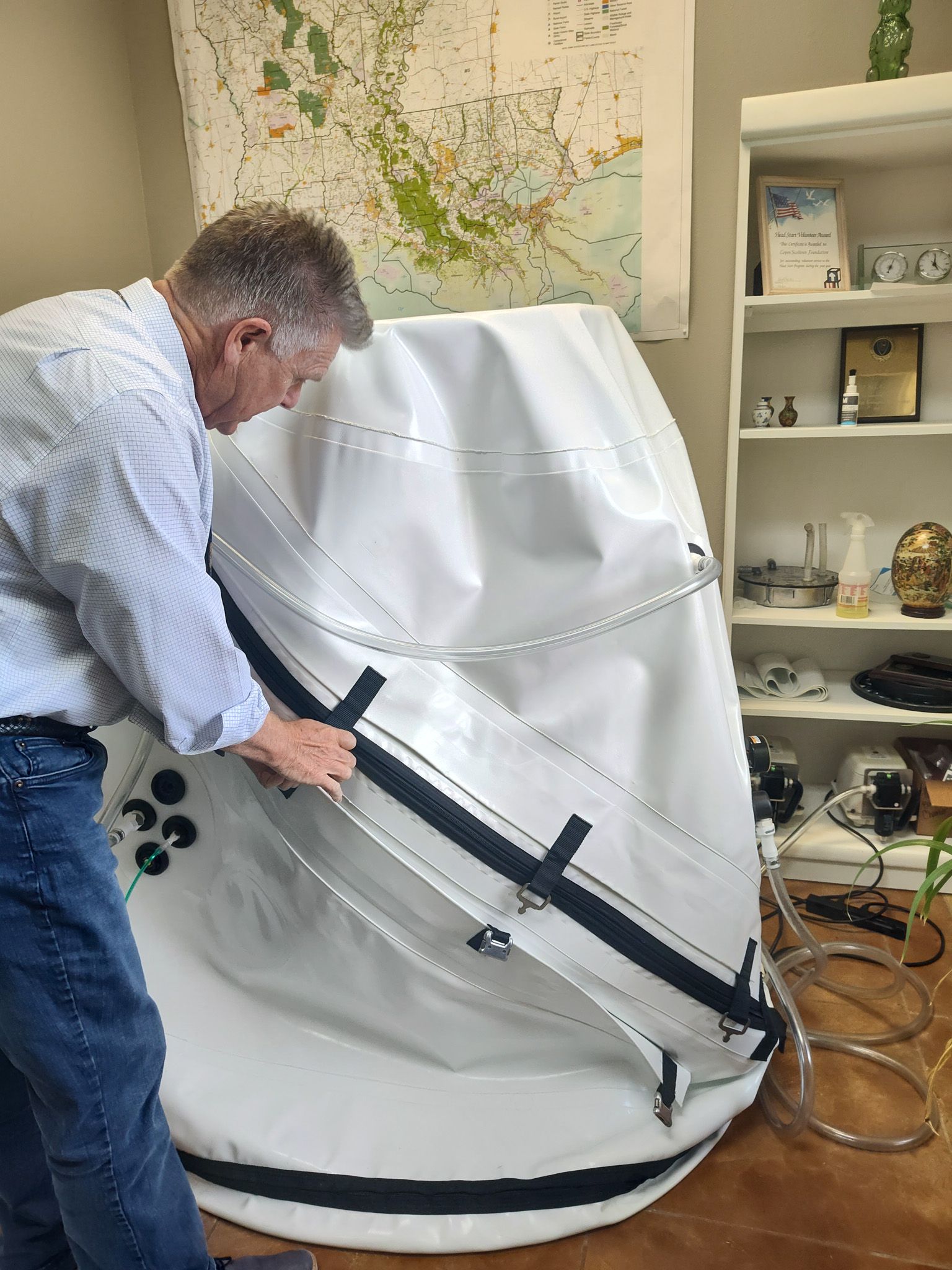 A man is standing next to a large white oxygen chamber