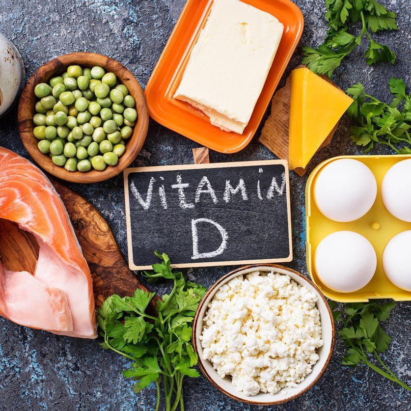 A chalkboard with the word vitamin d written on it surrounded by various foods.