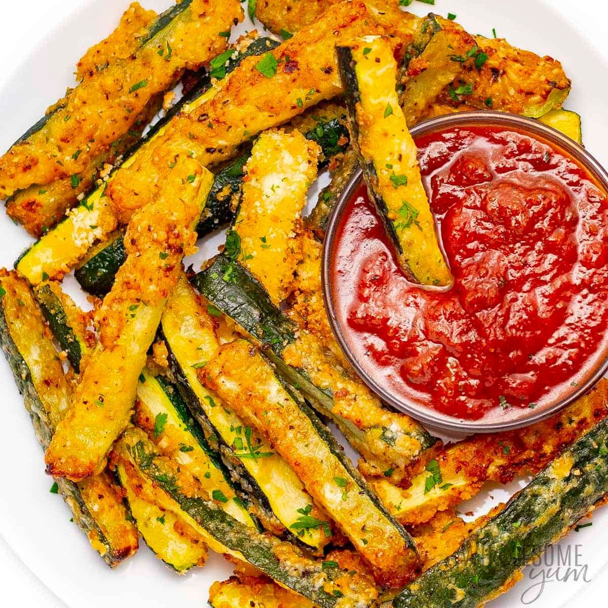 A white plate topped with fried zucchini sticks and a bowl of ketchup.