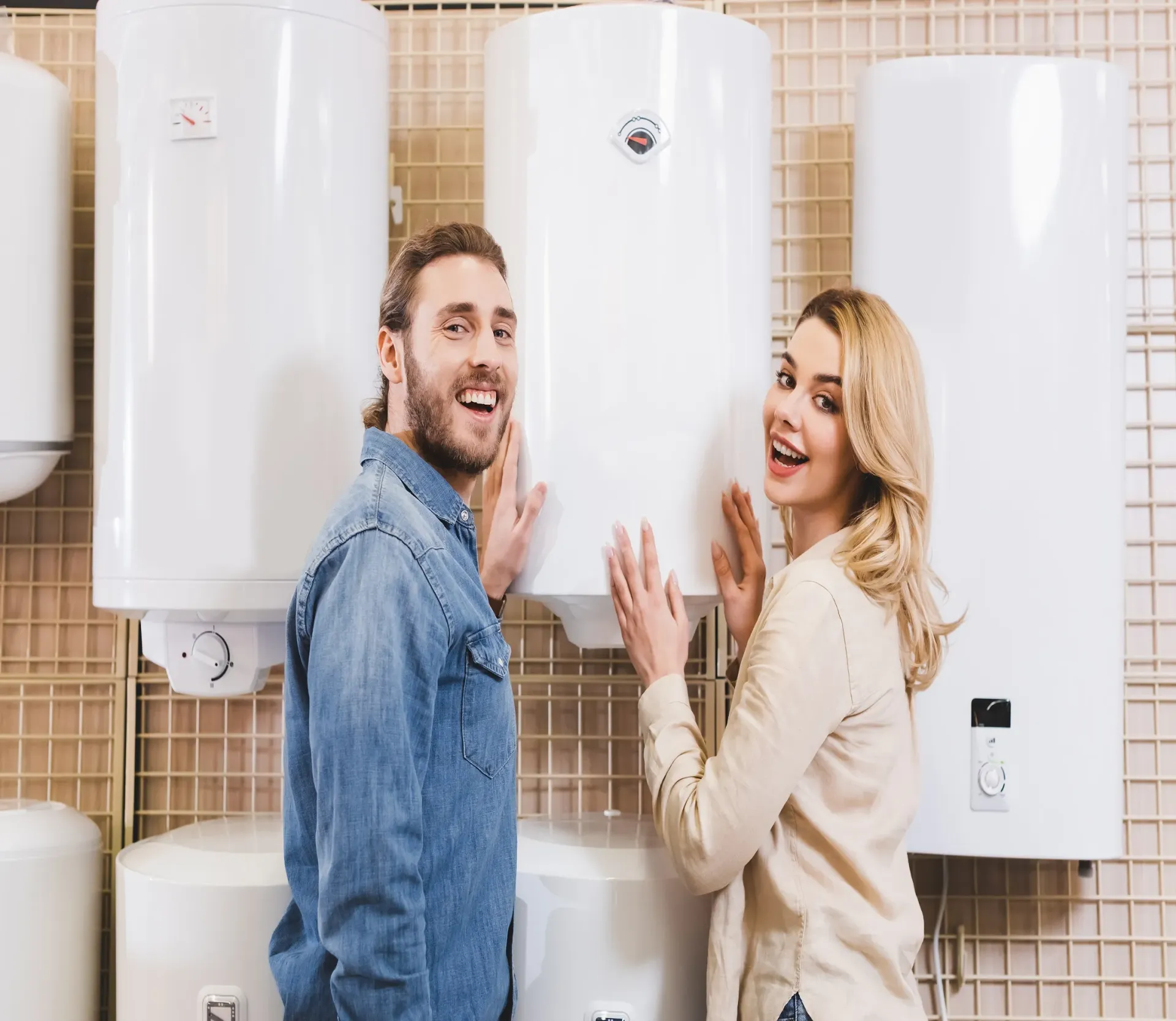 A man and a woman are standing next to each other in front of a wall of water heaters.