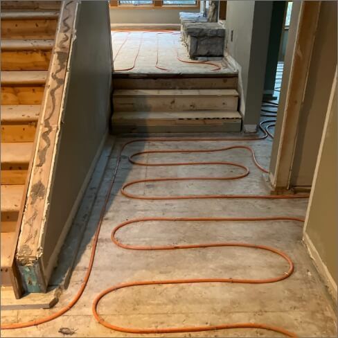A hallway with a staircase and a bunch of wires on the floor