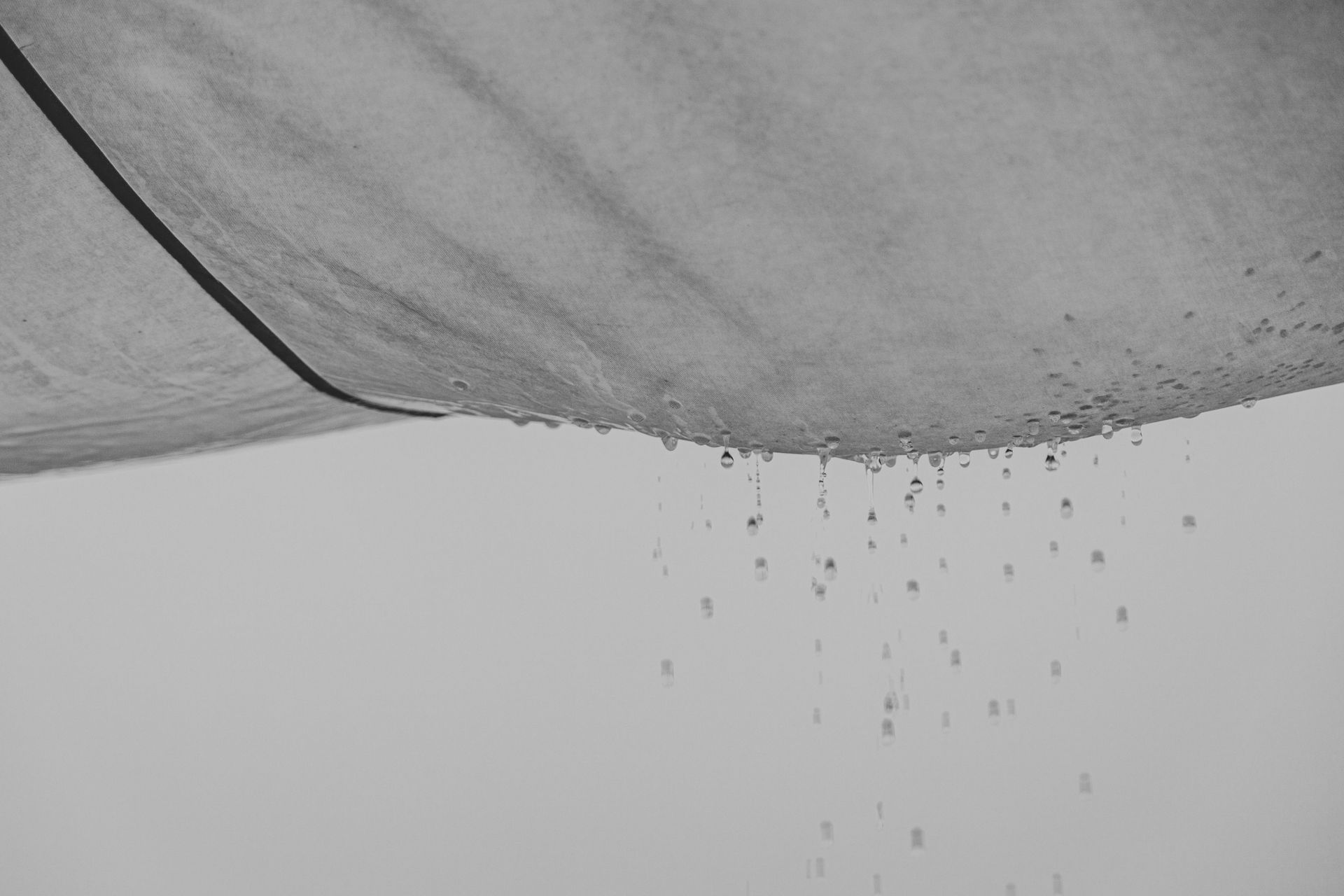 A black and white photo of water drops falling from a ceiling.