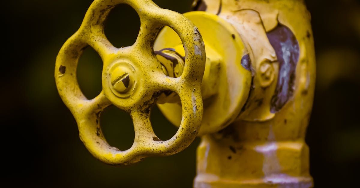 A close up of a yellow valve on a pipe.