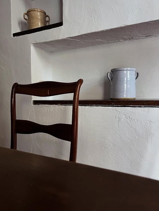 Una sedia di legno davanti a un tavolo marrone scuro.