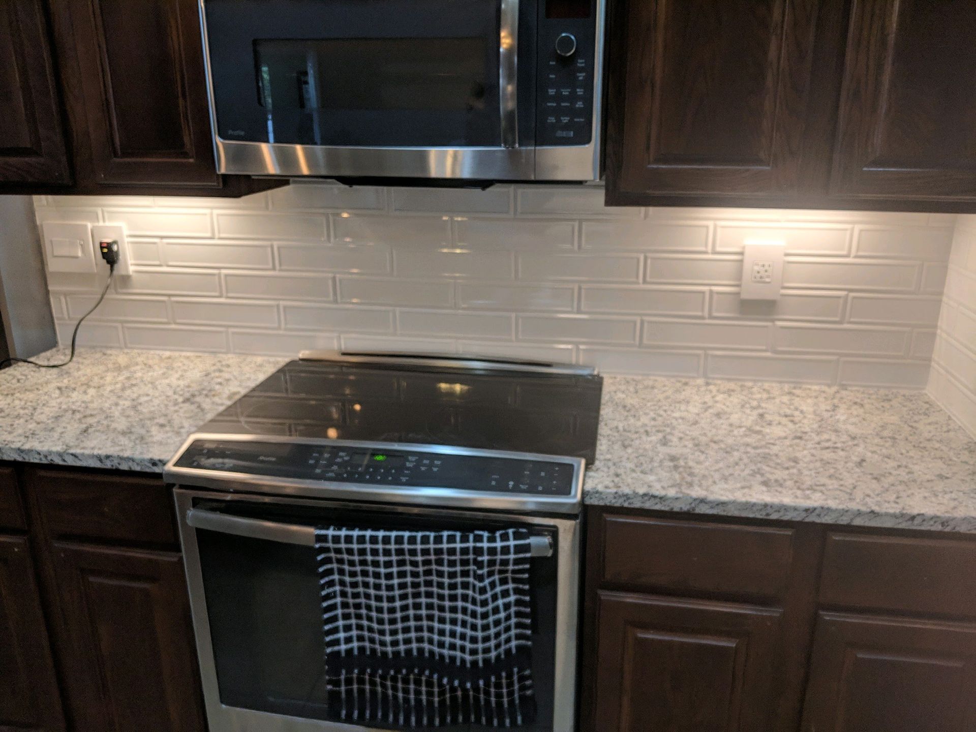 A modern kitchen featuring a stainless steel stove, microwave, speckled granite countertop
