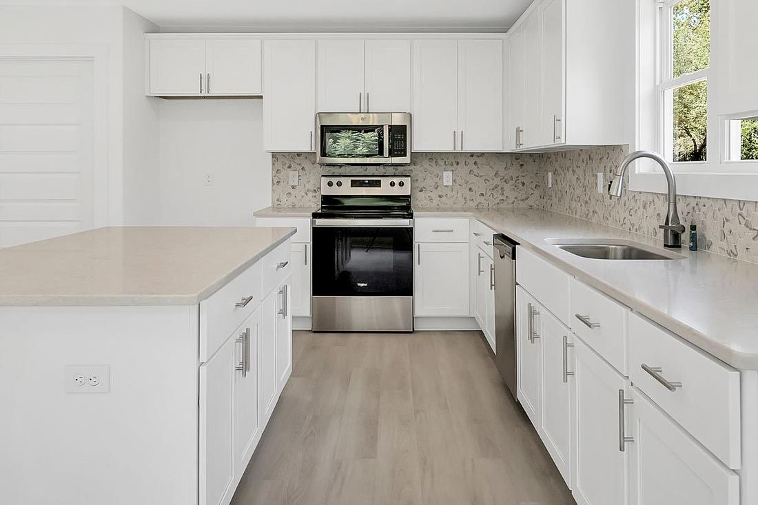 Modern kitchen with white cabinets, stainless steel appliances, a center island, and neutral countertops.