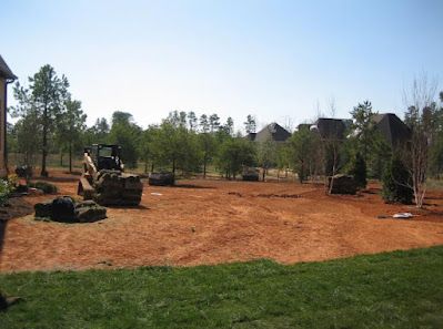 A large dirt field with a bulldozer in the middle of it.
