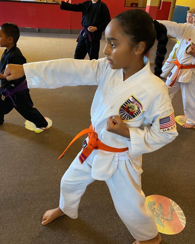 African-American kids wearing a white karate uniform with Orange Belt