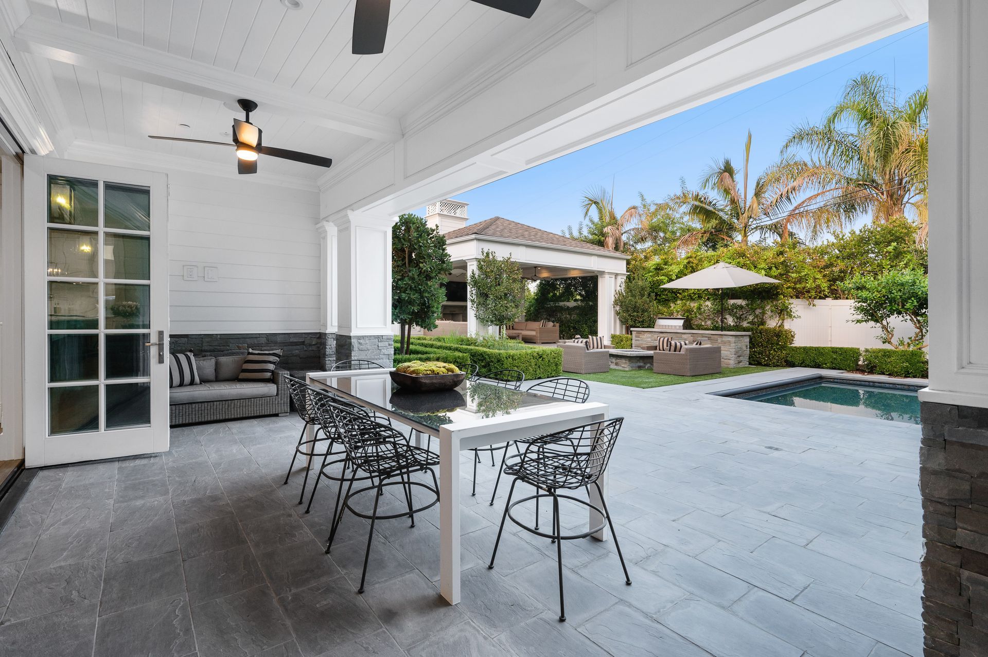 Covered patio with dining table and bar stools overlooking a pool and tropical garden Covered patio with dining table and bar stools overlooking a pool and tropical garden