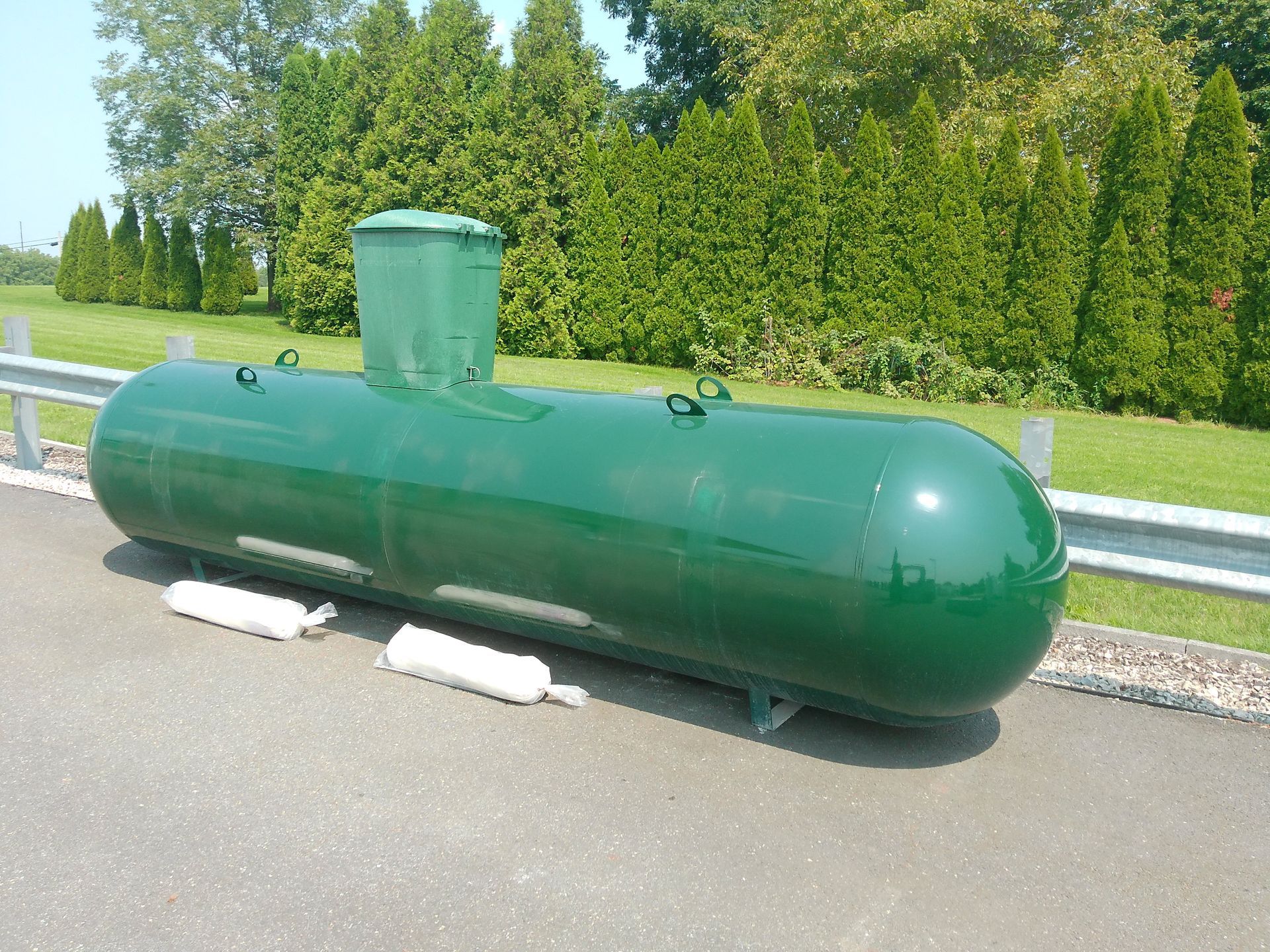 A Green Cylinder Is Sitting on The Side of The Road