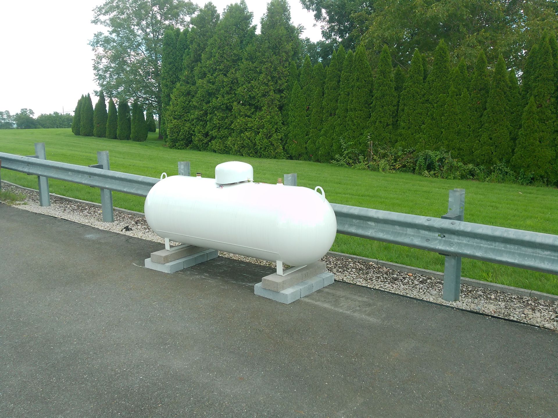 A White Propane Tank Sits on The Side of A Main Road