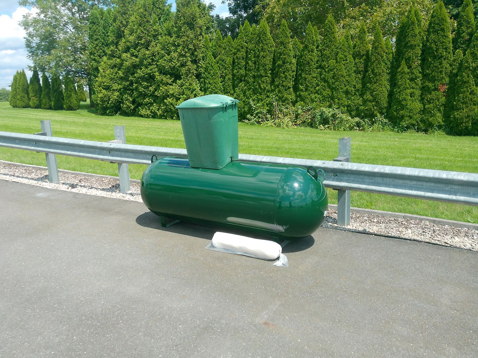 A Green Propane Tank Sits on The Side of The Road Far View