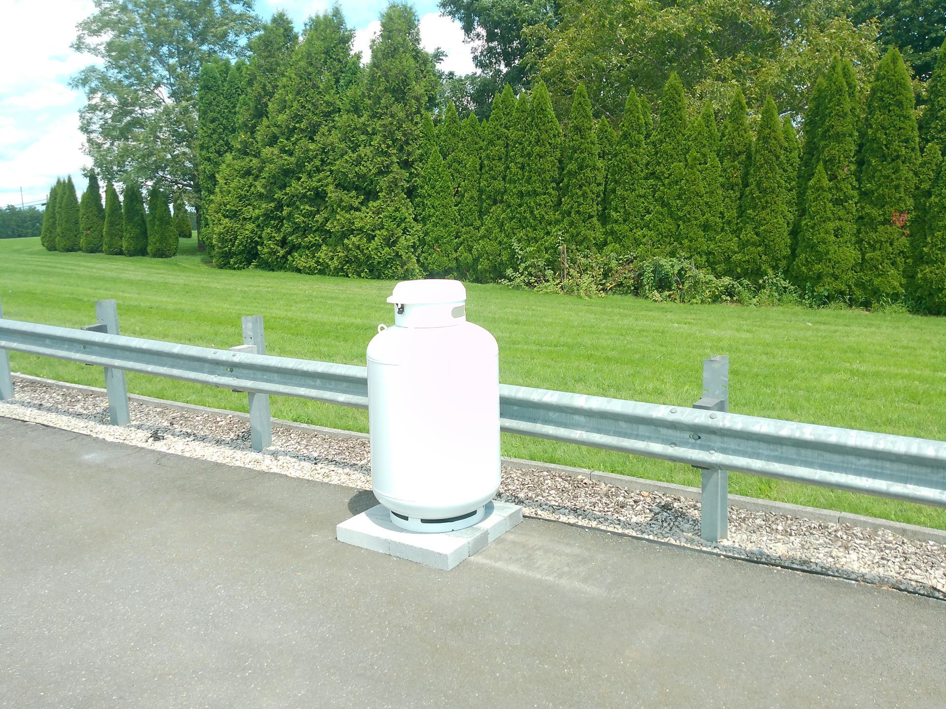 A White Propane Tank Sits on The Side of A Road