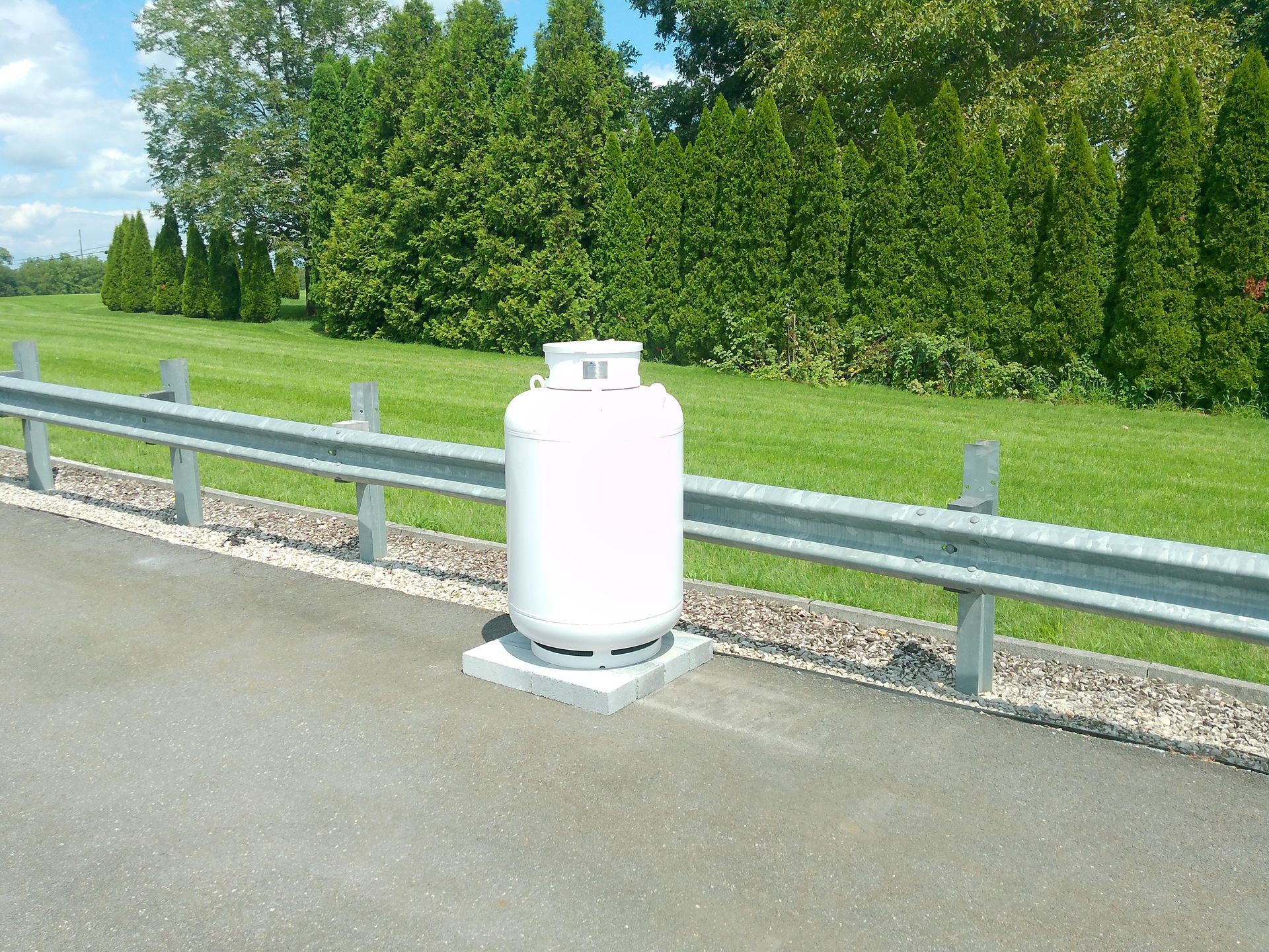 A White Propane Tank Is Sitting on The Side of A Road Standing