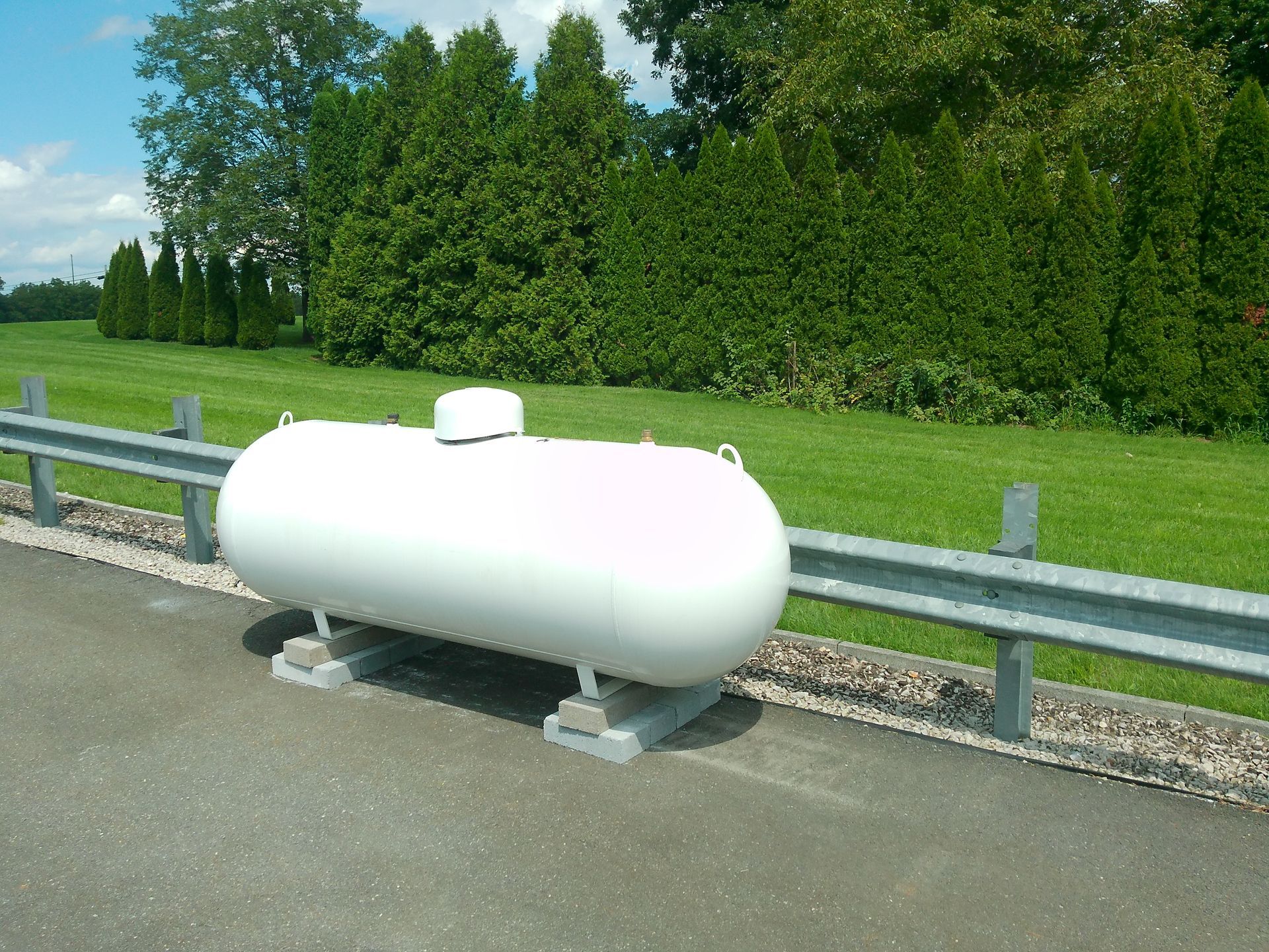 A White Propane Tank Sits on The Side of The Road Far View