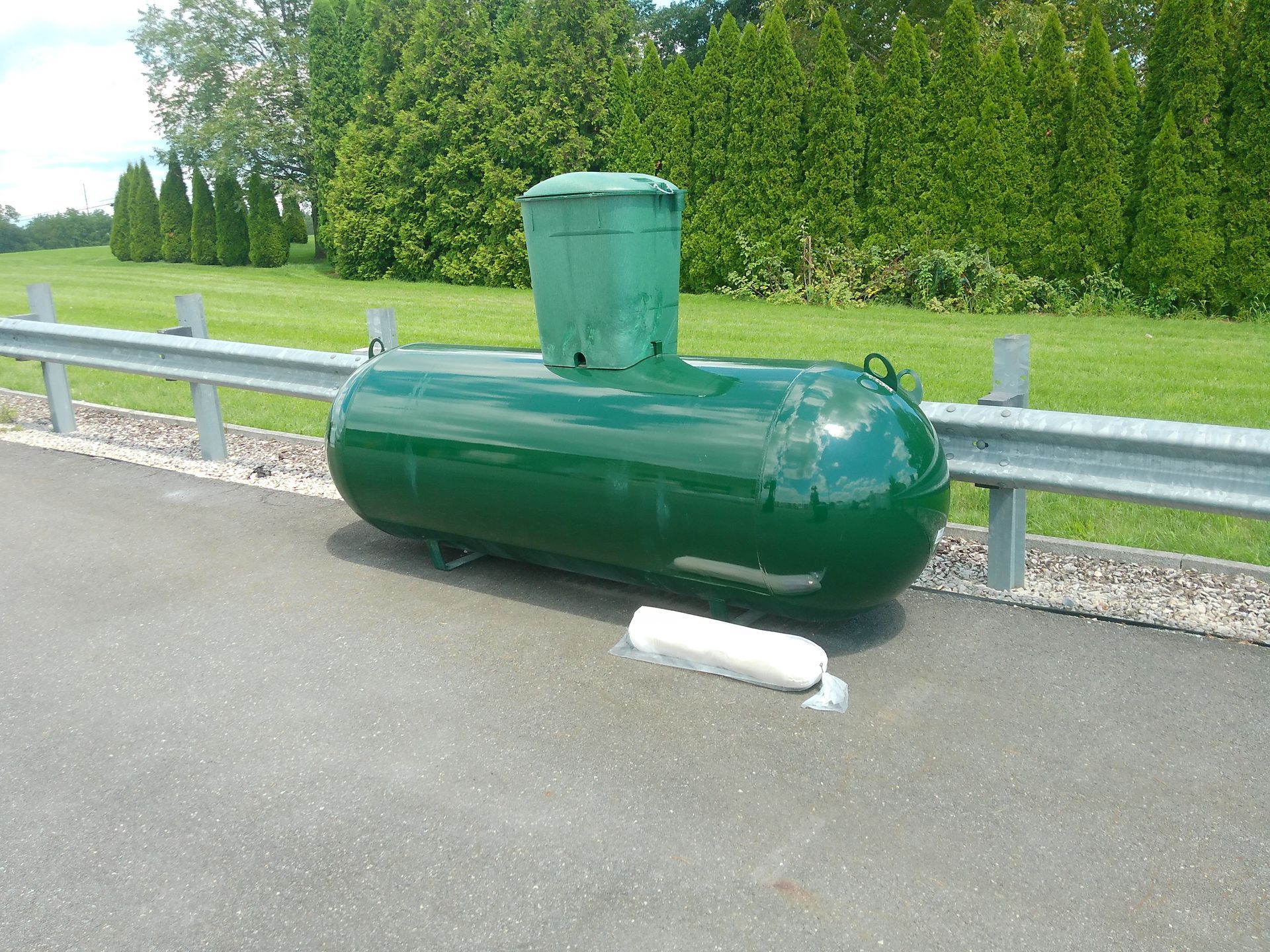 A Green Propane Tank Is Sitting on The Side of The Road