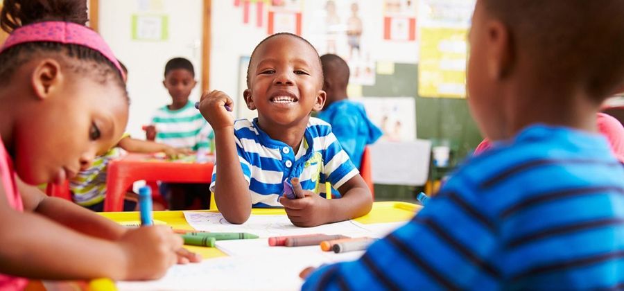 A group of children are sitting at a table in a classroom.