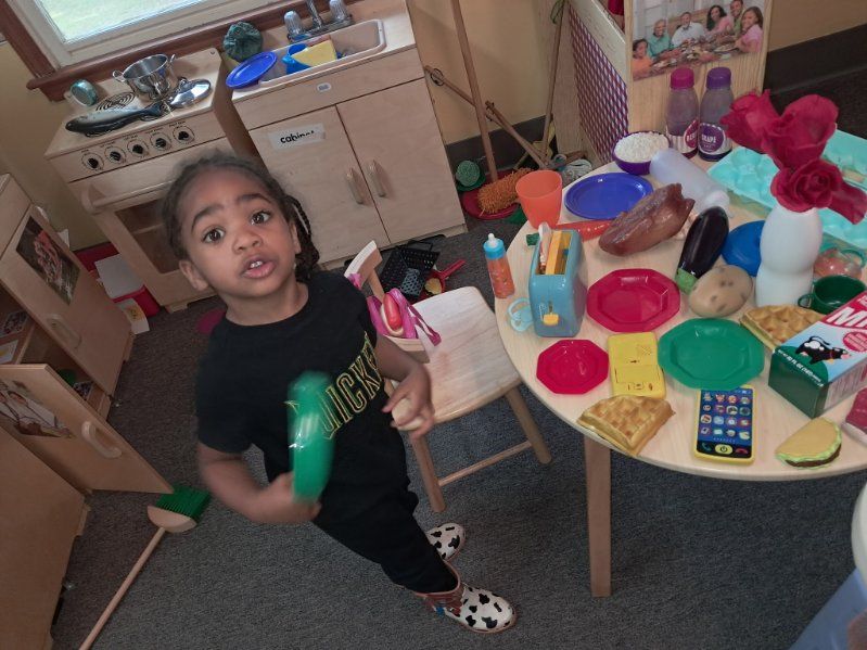 A little girl is standing in front of a table full of toys