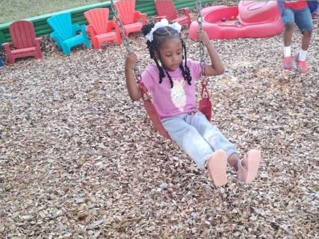 A little girl is standing in front of a table full of toys
