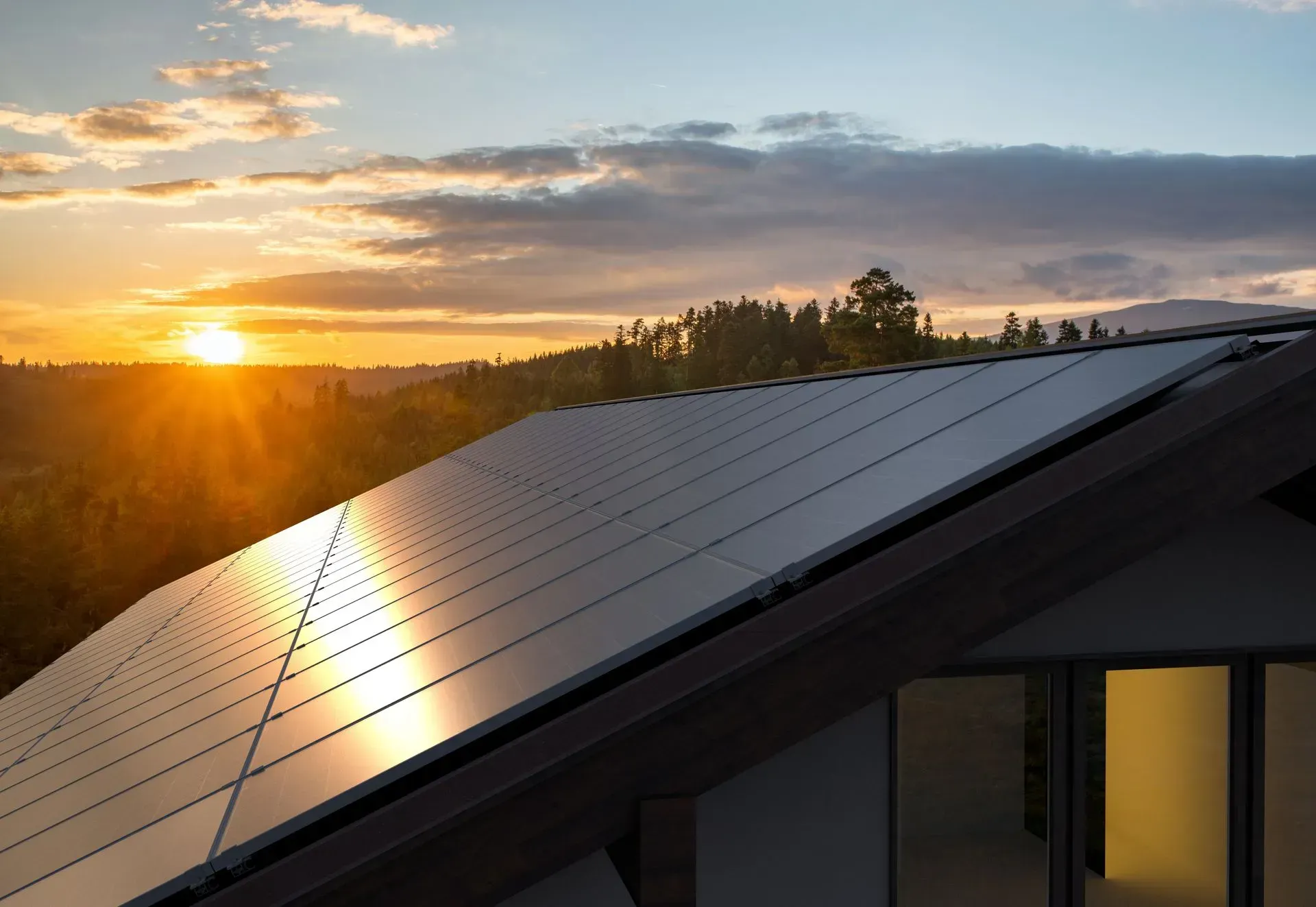 A roof with solar panels on it at sunset.