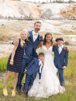 Family, including bride and groom, pose in front of a Yellowstone National Park hot spring.
