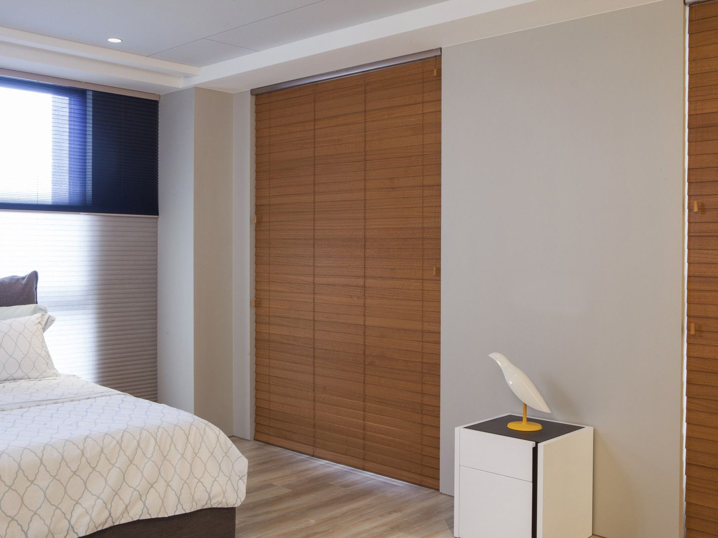 Bedroom with woven wood blinds, bed, nightstand, and window.