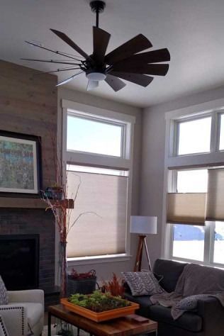 Living room with modern ceiling fan and windows; fireplace and couch are visible.