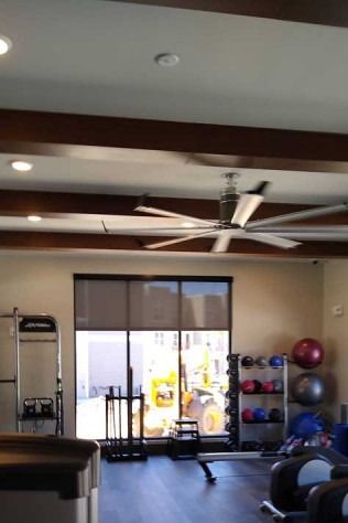 Gym interior with exercise equipment, large fan, and a window with construction outside.