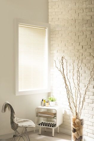 Bathroom corner with window, blinds, brick wall, chair, and decorative vase.