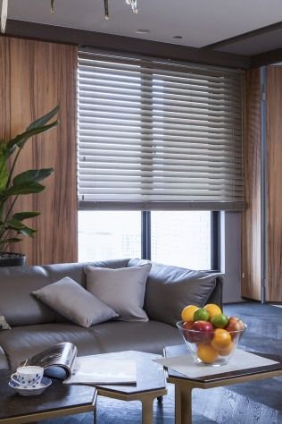 Living room with brown blinds, leather sofa, wood paneling, and a coffee table with fruit.
