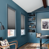 Blue room with two windows, built-in shelves, desk, and wooden chair; gray shades.