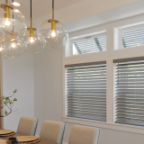 Dining room with orb pendant lights, gray blinds, and beige chairs.