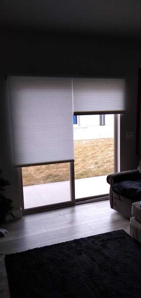 A sliding glass door with blinds is closed, with a dark area rug, a couch and outside lawn visible.